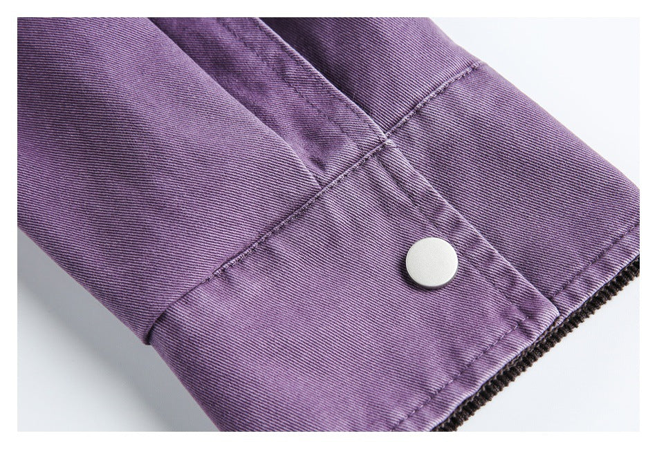 Close-up of a purple sleeve cuff with a round silver snap and stitched panels.