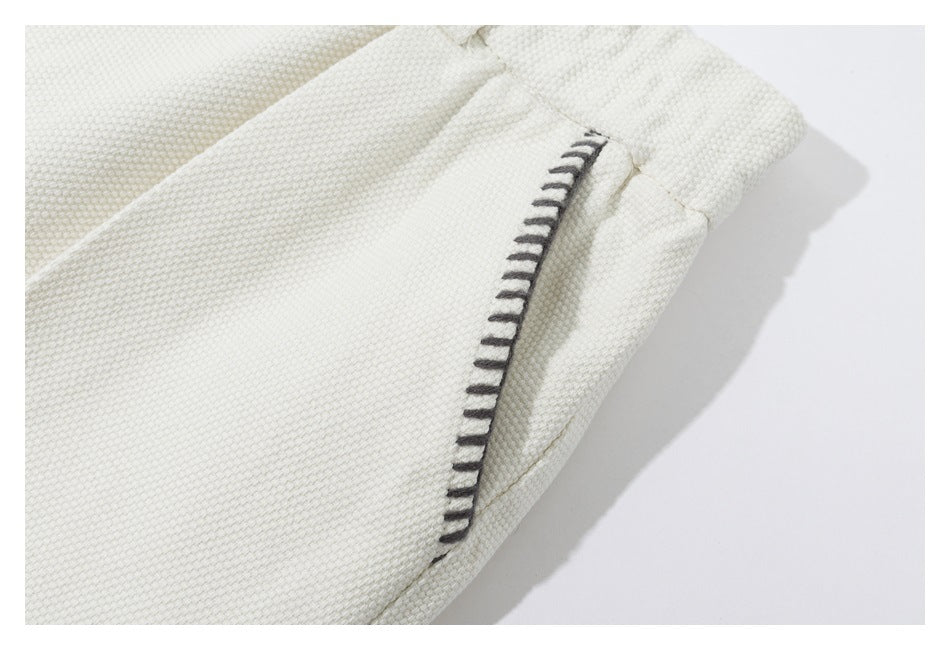 Close-up of an ivory textured garment seam with dark contrast stitching.