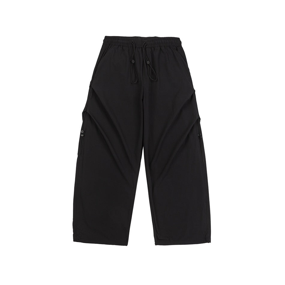 Black wide-leg pants with elastic drawstring waist, side pleats and side-seam pull details, flat lay front view