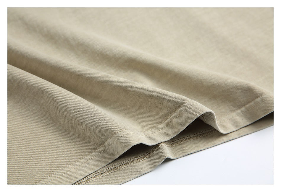 Close-up of a beige garment hem showing folded stitching and overlock seams.