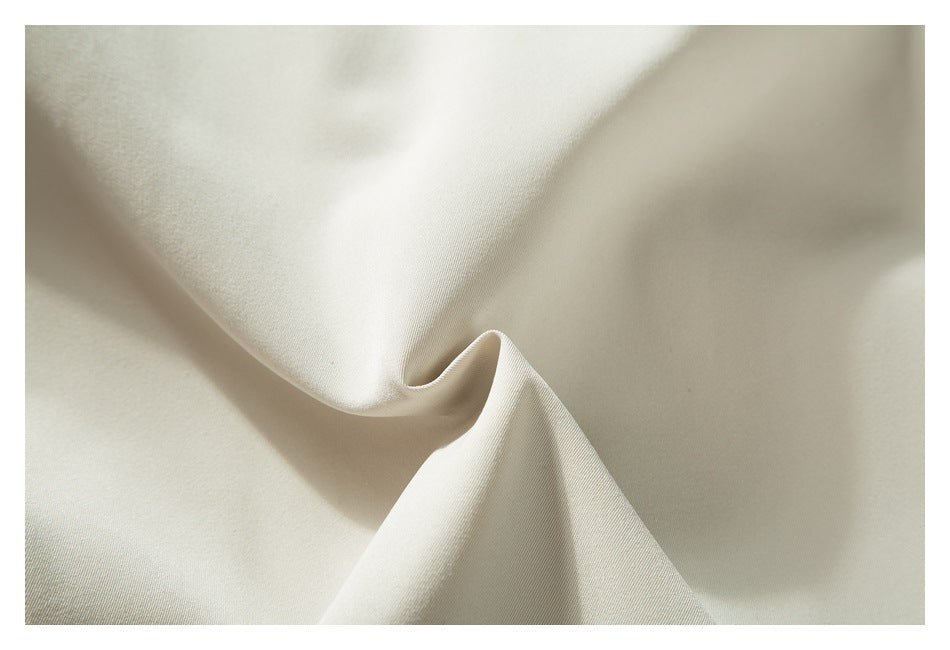Close-up of smooth ivory fabric draped into soft folds.