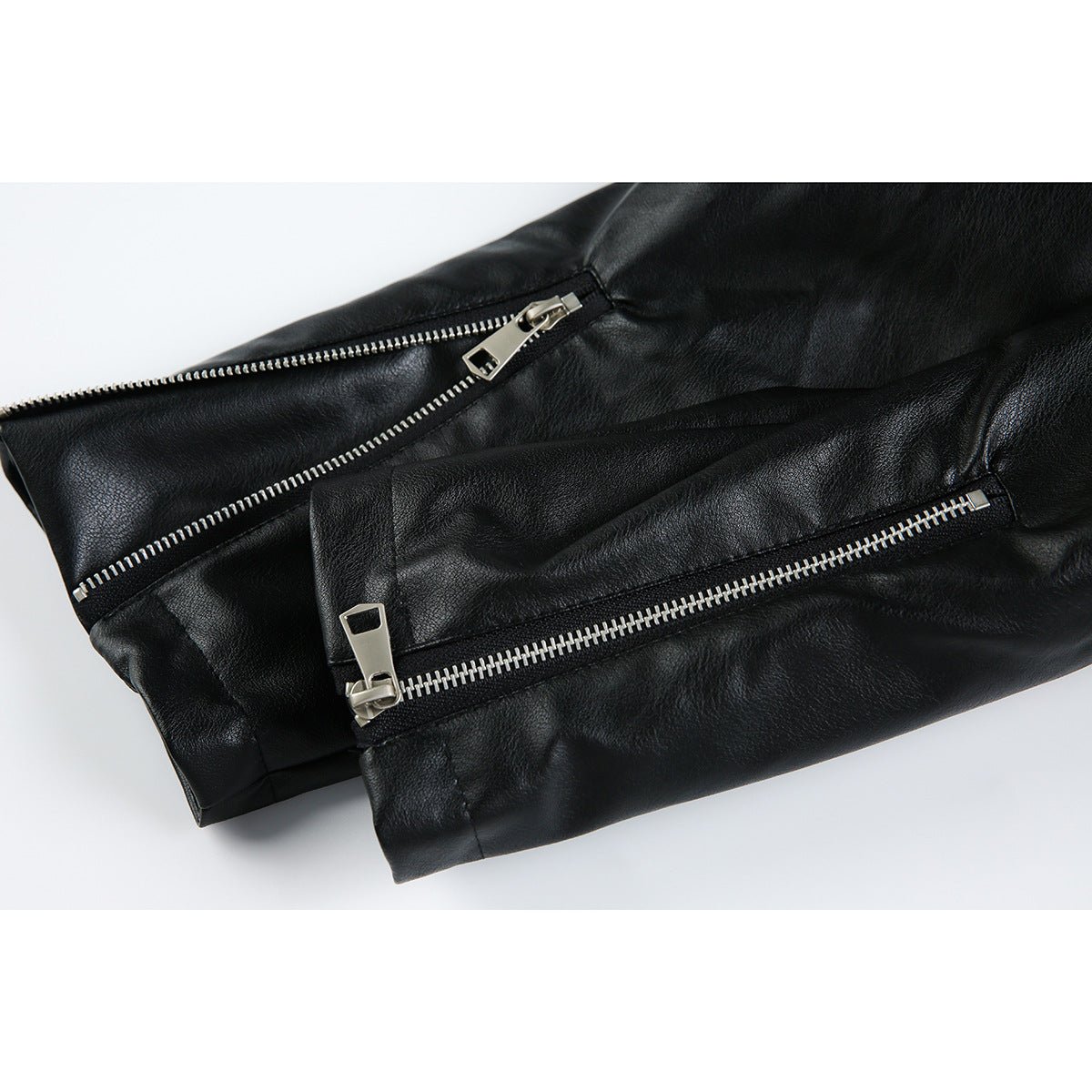 Close-up of a black jacket sleeve with two silver zippers.