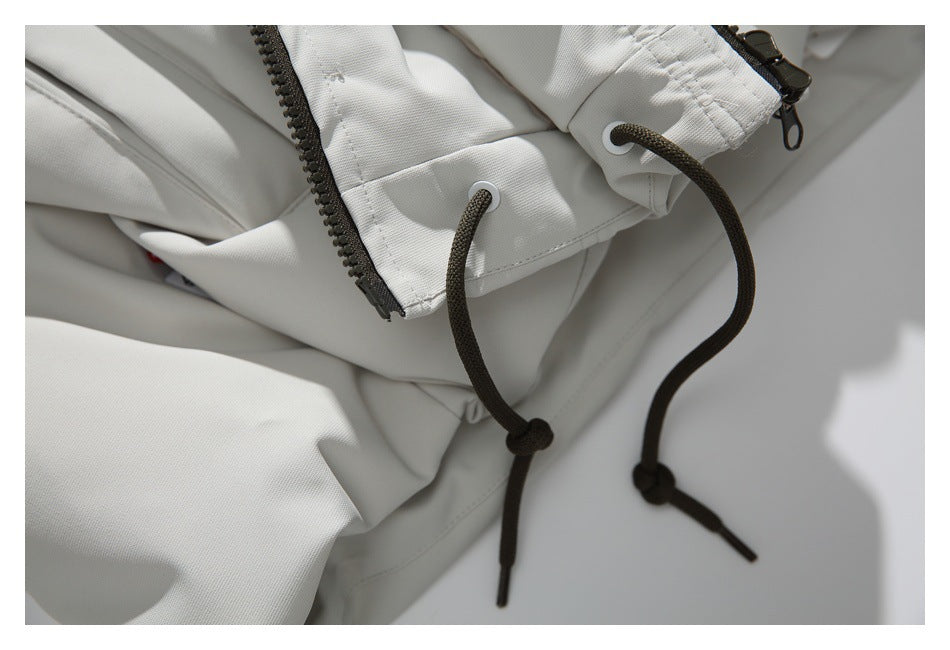 Close-up of a white jacket zipper, eyelets, and dark adjustable drawcords with knotted ends.