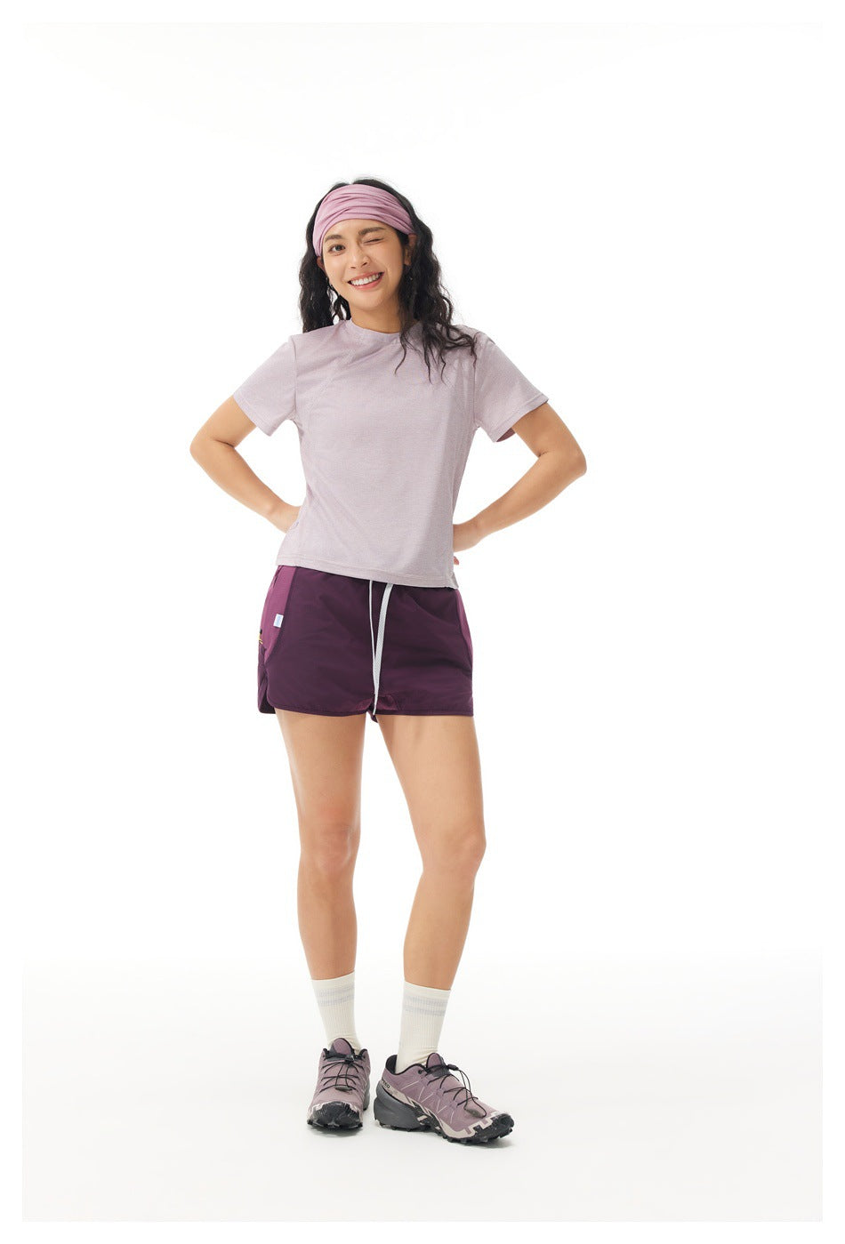 Woman modeling a pale lilac short-sleeve shirt and plum running shorts, front view on a white background.