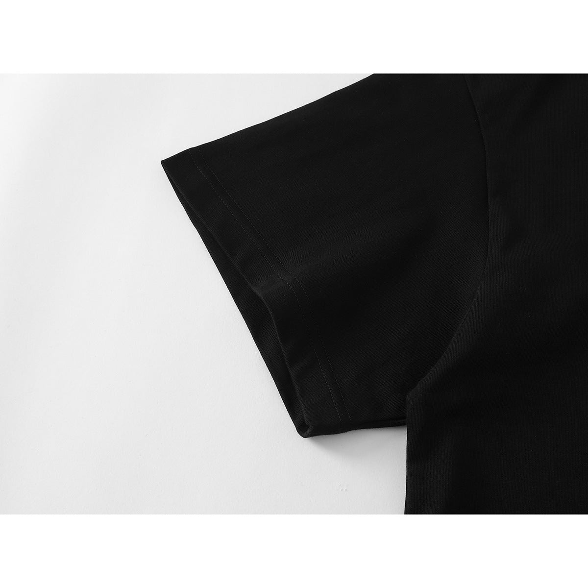 Close-up of the black T-shirt's short sleeve and stitched hem.