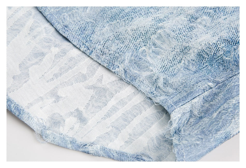 Close-up of the frayed edge and printed reverse side of light blue denim fabric.
