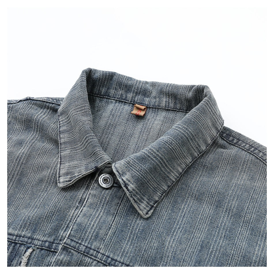 Close-up of the washed denim jacket's pointed collar, top button, stitching, and inner neck label.
