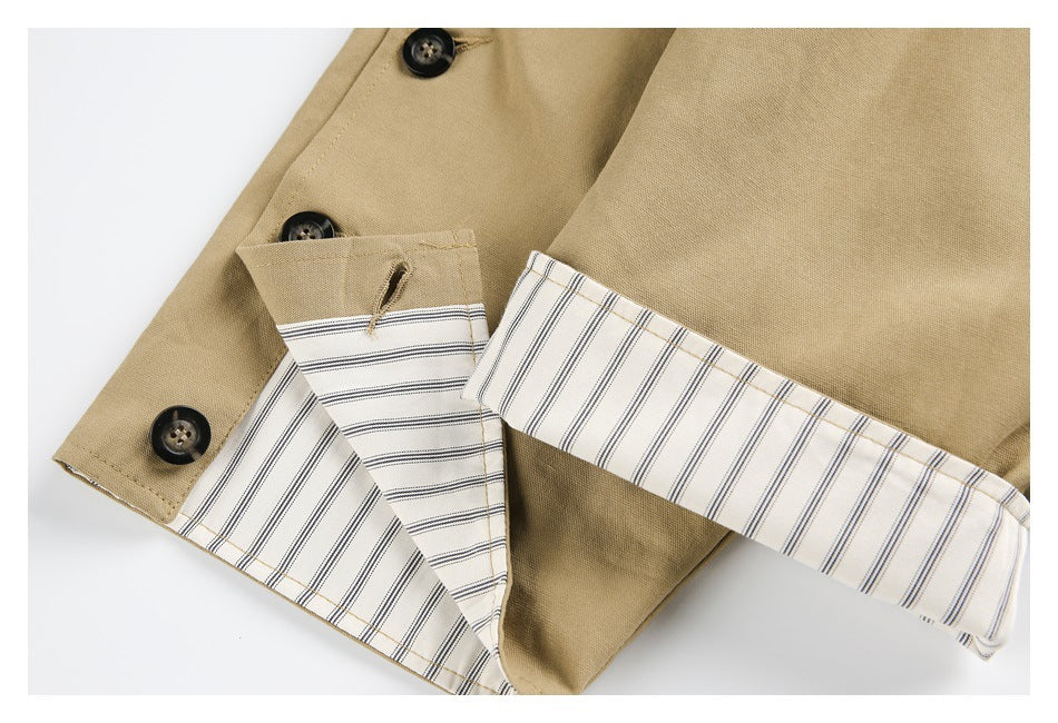 Close-up of a tan garment with dark buttons and cream lining in thin stripes.