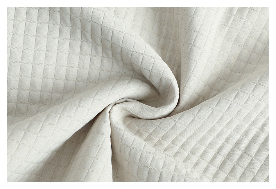 Close-up of ivory fabric with a raised square grid pattern, loosely folded.