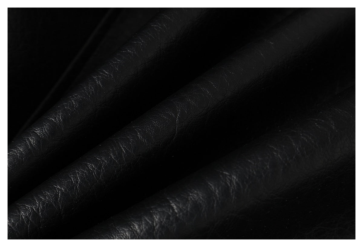 Close-up of black pebbled leather-like material arranged in soft folds.