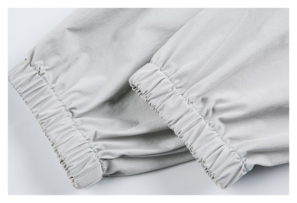 Close-up of pale gray garment fabric with two gathered elastic cuffs.