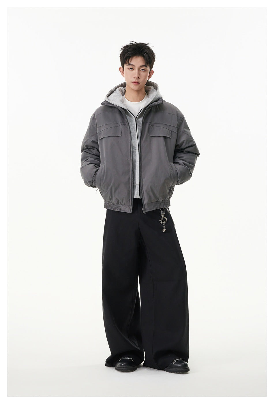 Full-length view of a model wearing a gray zip jacket over a gray hoodie with black wide-leg pants.