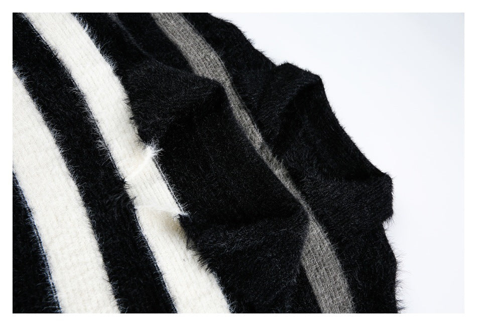 Close-up of fuzzy black knit with broad ivory and gray stripes and a folded edge.