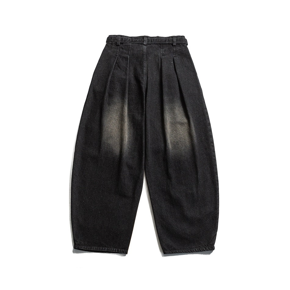 Back view of black tapered trousers with a high waist, belt loops, and subtle faded patches.
