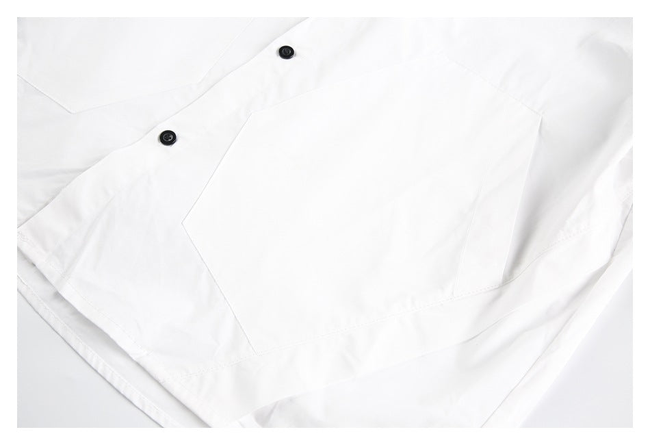 Close-up of a large angular patch pocket and black buttons on a white shirt.