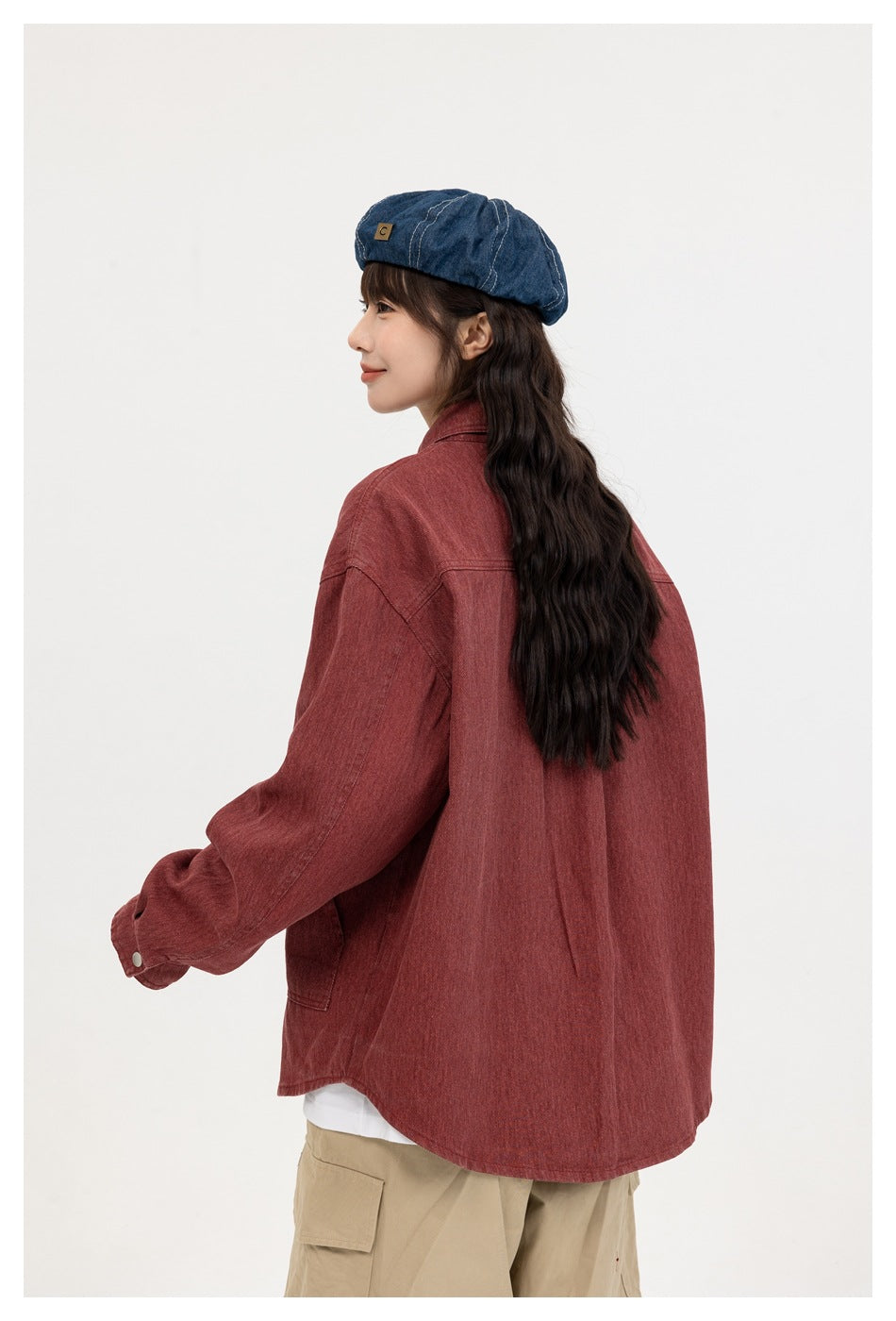 Rear view of a model wearing a muted red overshirt with a long curved hem and loose sleeves.