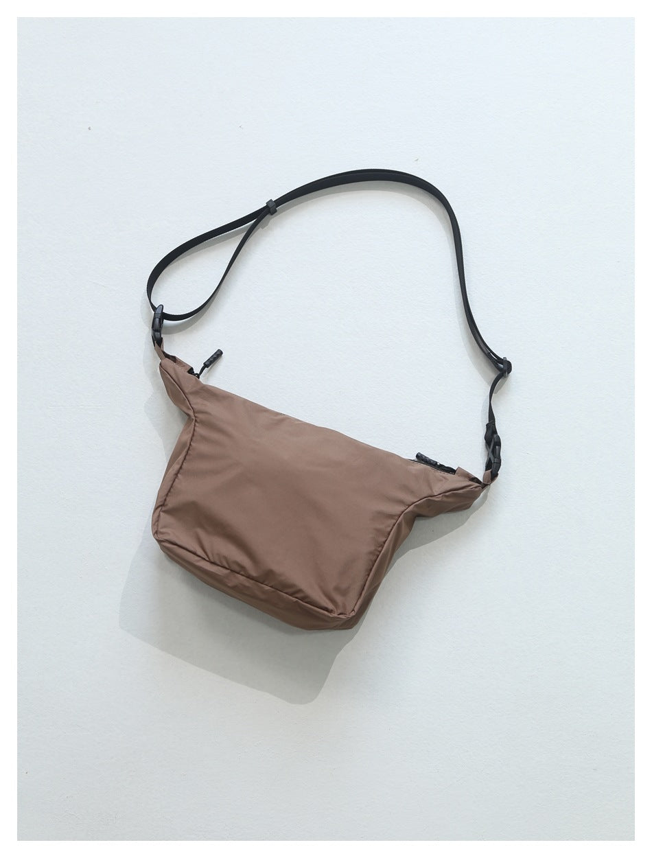 Brown crossbody bag with a wide black adjustable strap, shown against a white background.