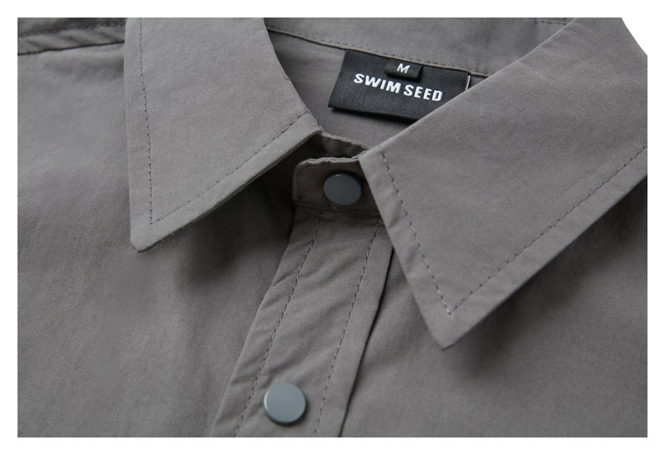 Close-up of the gray shirt's pointed collar, snap button, and SWIM SEED neck label.