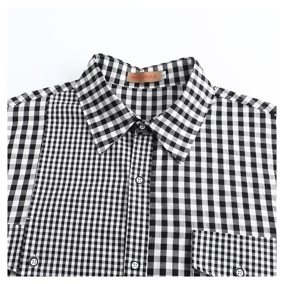 Close-up of the collar and upper front of a black-and-white check shirt, with buttons and contrasting checks.