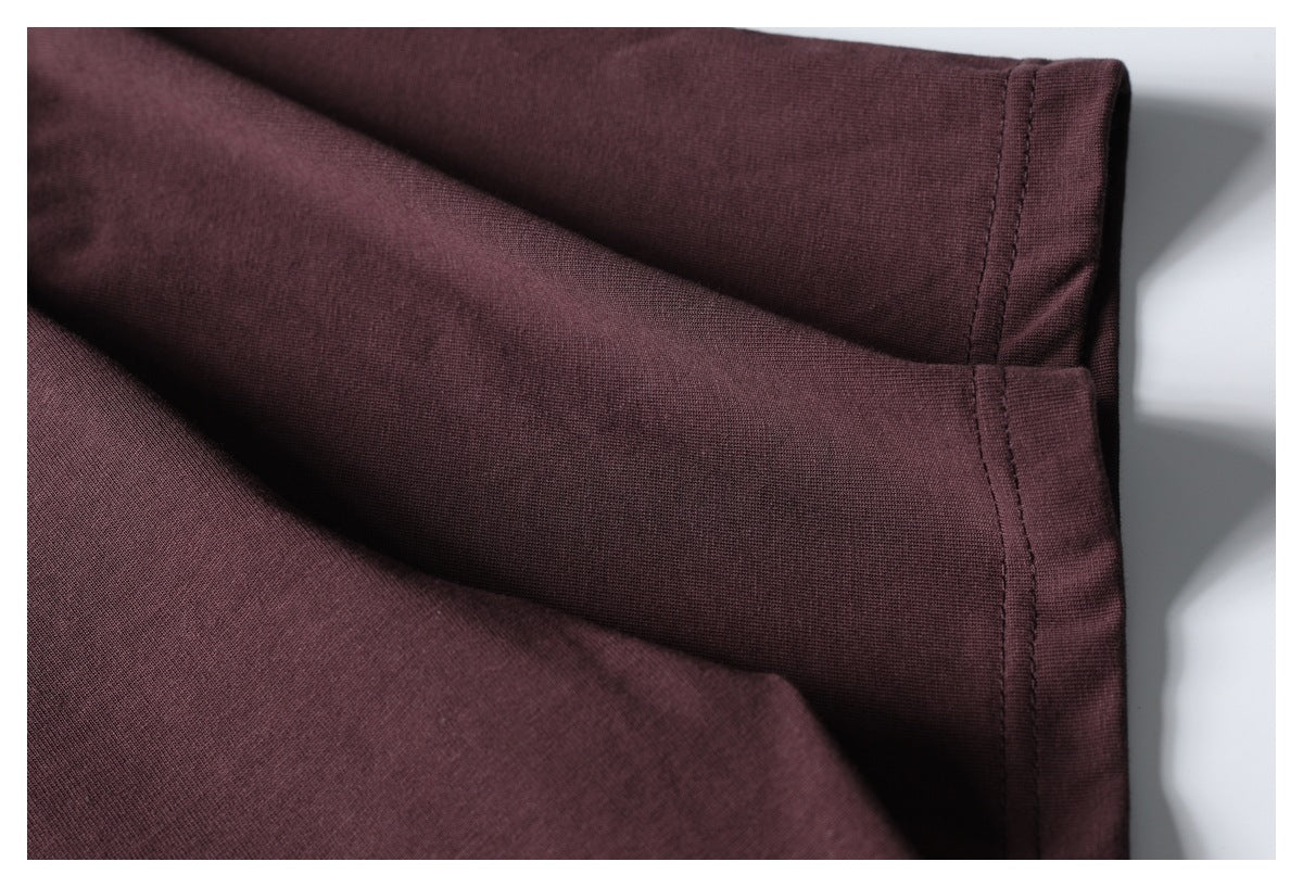 Close-up of a burgundy T-shirt sleeve edge and stitched seam against a white background.
