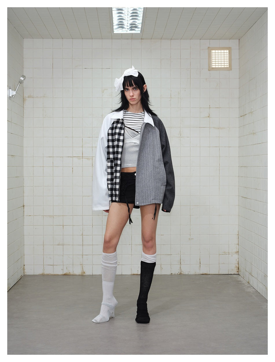 Full-length view of a model wearing a white, black-check, gray pinstripe, and charcoal color-block jacket.