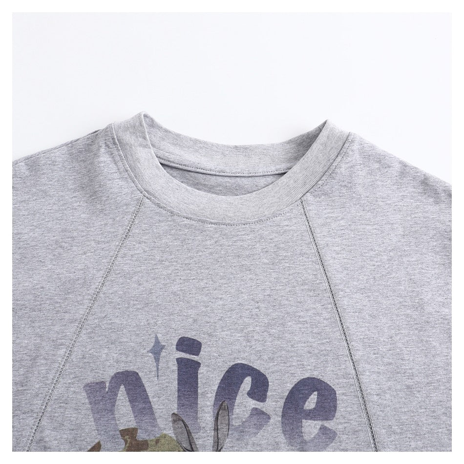 Close-up of the heather-gray T-shirt neckline, raglan seams, and upper portion of its chest graphic.