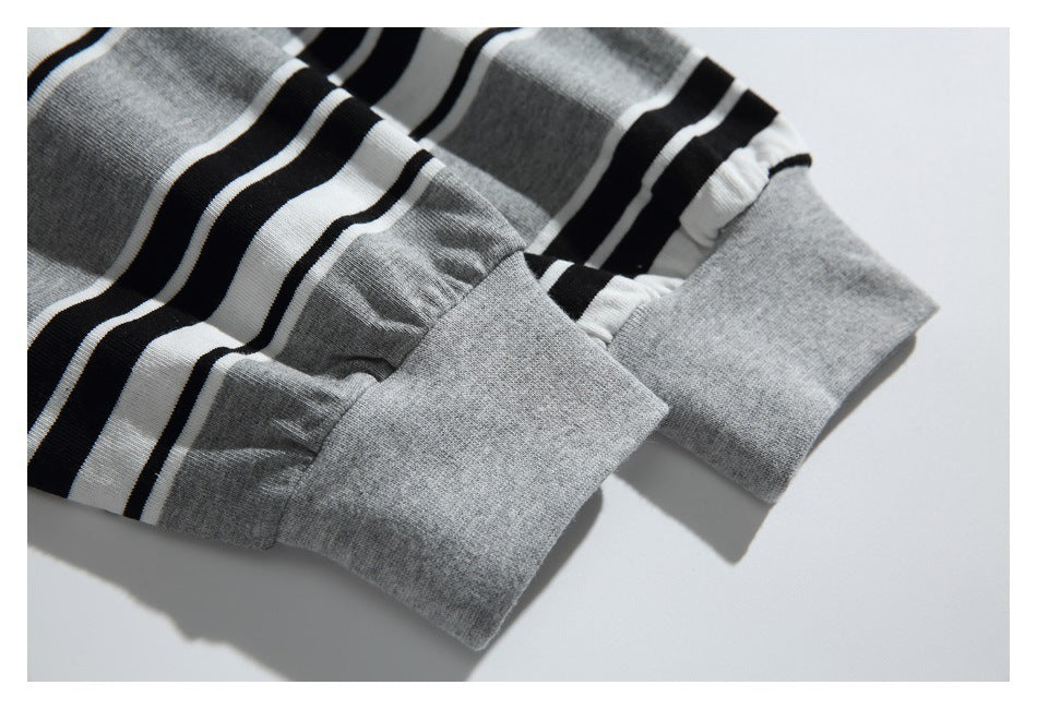 Close-up of two wide solid-gray cuffs on a gray, black, and white striped knit garment.