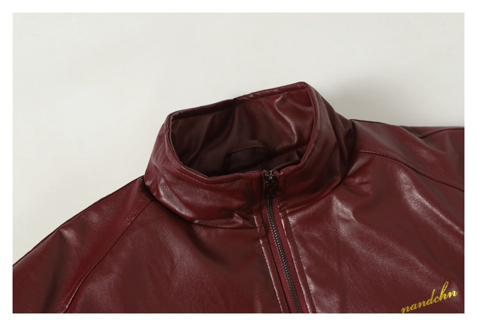 Close-up of a burgundy jacket's stand collar and zipper, with gold script embroidery near the edge.