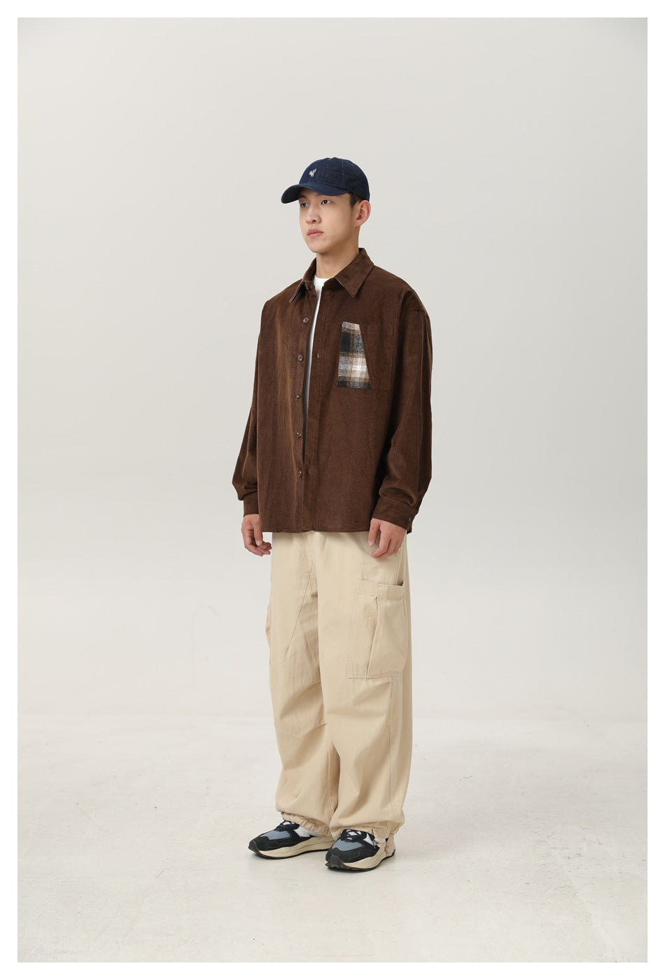 Model wearing brown corduroy shirt with plaid pocket panel over a white tee, angled side view