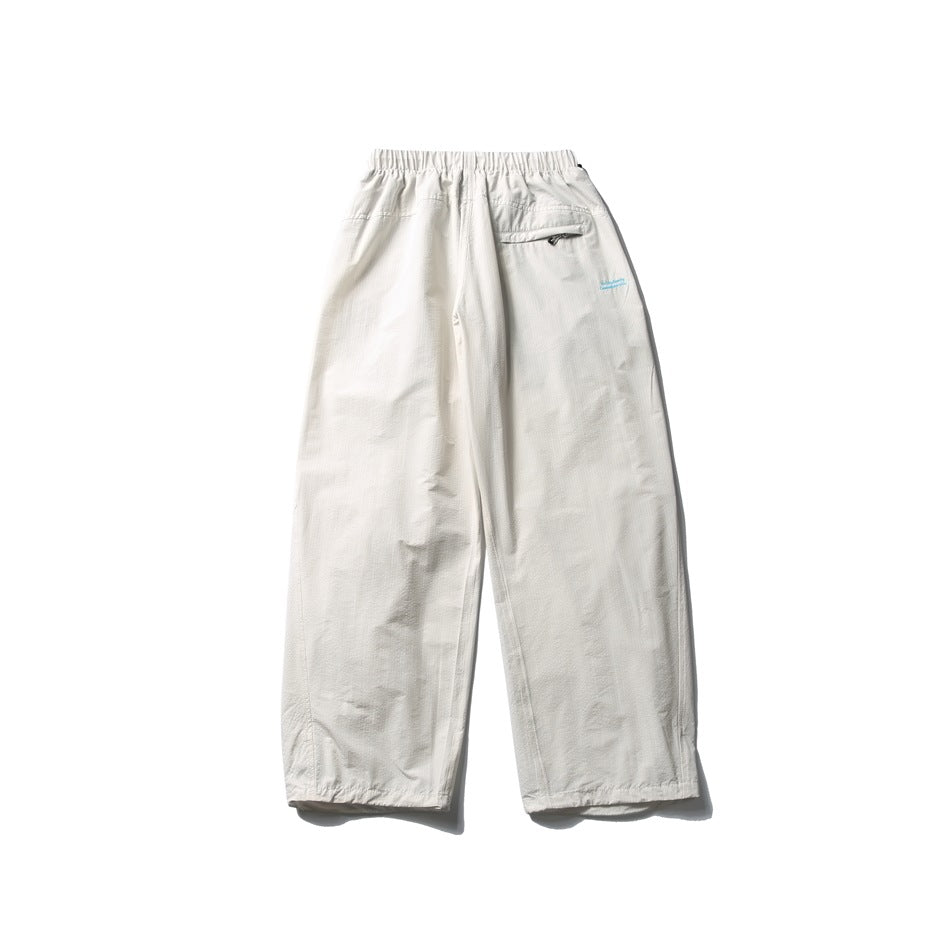 Off-white wide-leg pants laid flat, with an elastic waist and a small zip pocket at the back.