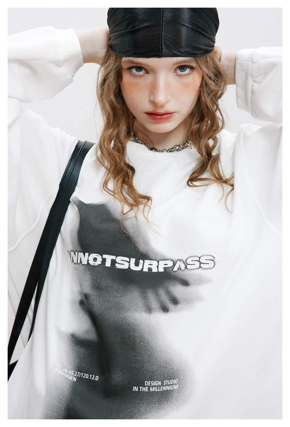 Close-up of a model wearing a white top with a large black graphic and English lettering.