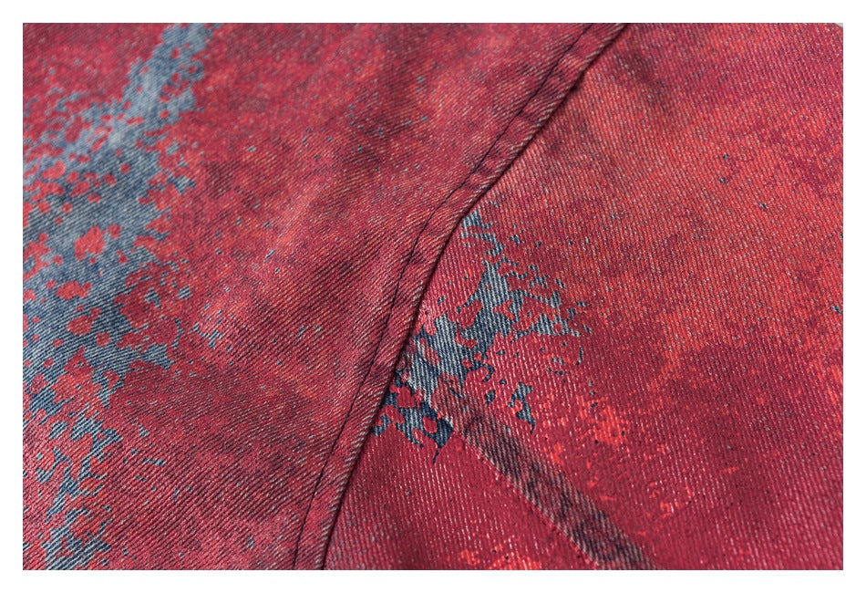 Close-up of a curved stitched seam across blue denim with distressed red coloring.
