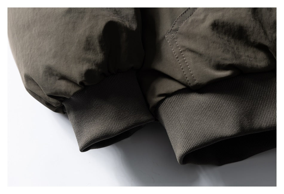 Close-up of a dark olive jacket sleeve gathered into a wide ribbed cuff.
