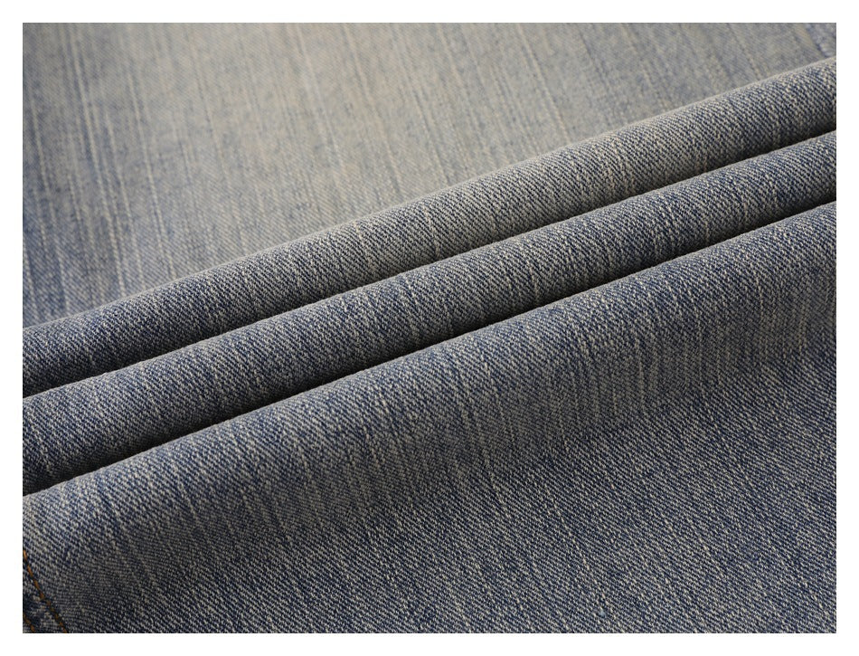 Close-up of faded blue denim folded into ridges, showing its diagonal weave and washed texture.