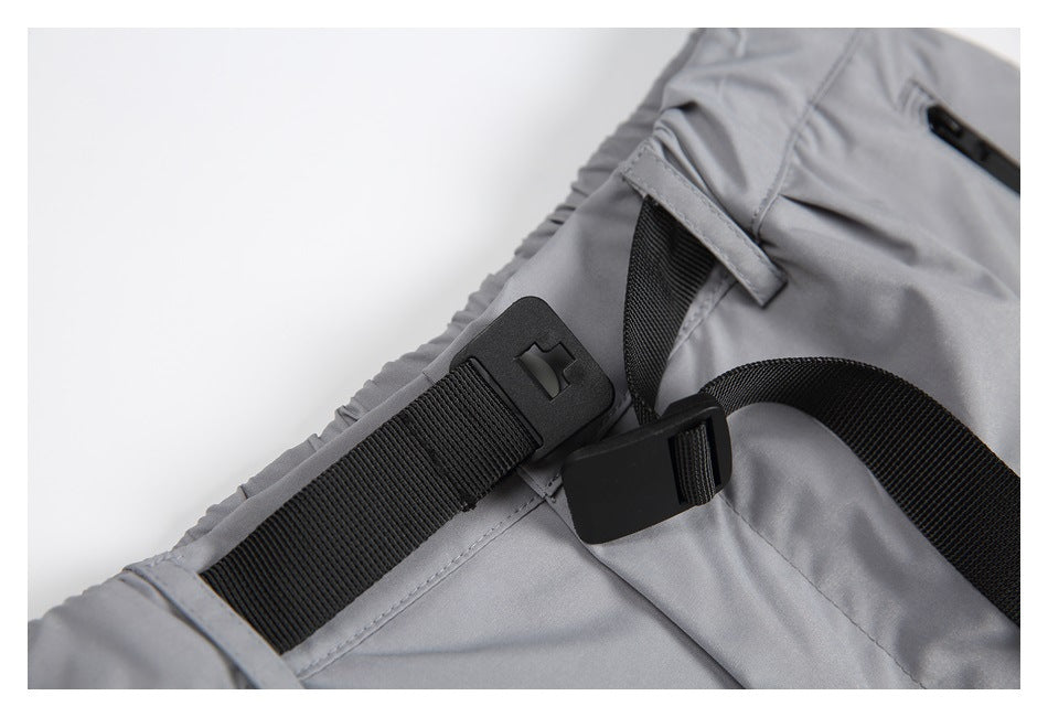 Close-up of gray pants showing a black adjustable webbing strap and buckle at the waist.