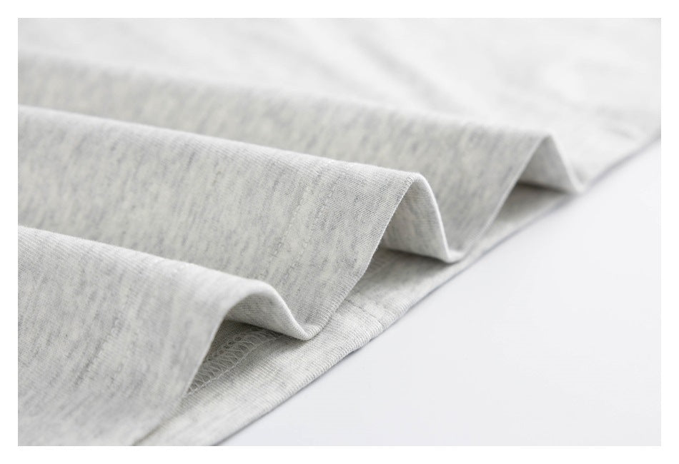Close-up of the folded edge and overlock stitching on a light gray heather shirt.
