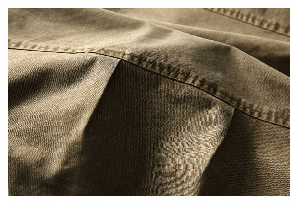 Close-up of khaki-brown fabric with a curved stitched seam and panel.