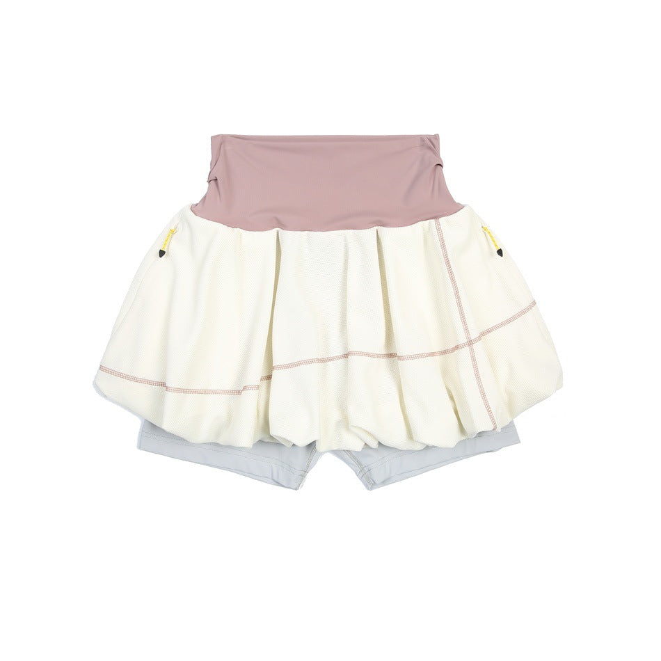 Cream skort with mauve-pink waistband, pink contrast stitching, side zip pockets and light gray inner shorts