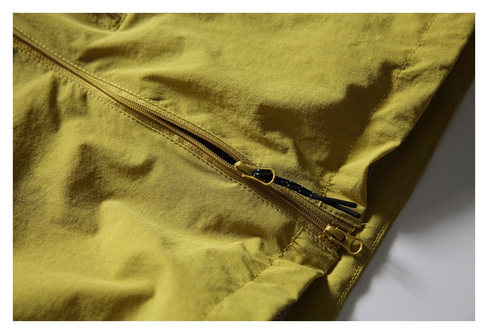 Close-up of a yellow garment with a diagonal zipper and black pull cords.