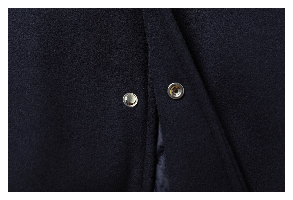 Close-up of two silver snap-fastener halves on the navy garment front.