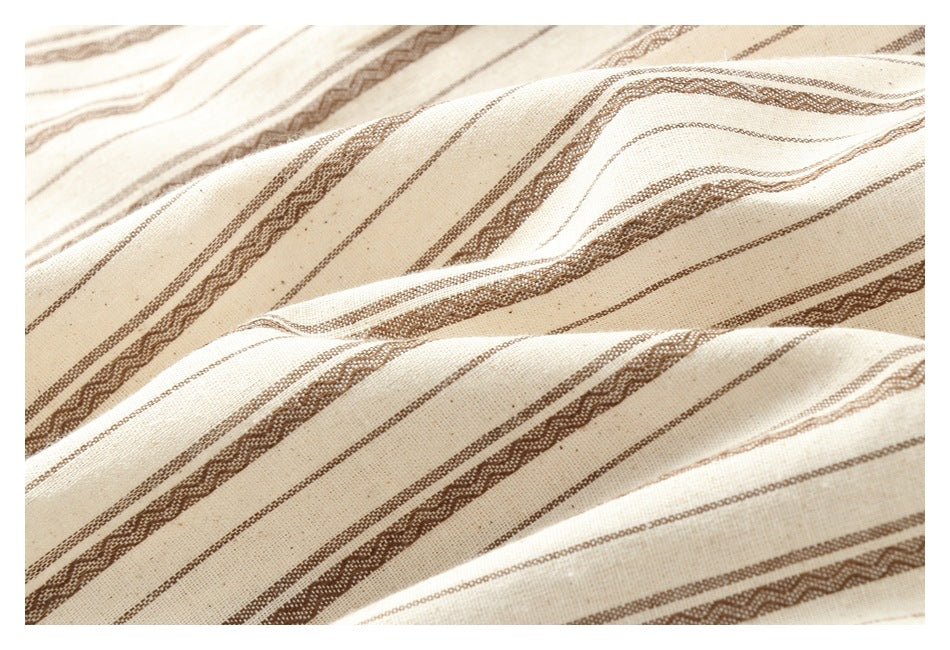 Close-up of cream-colored fabric with brown woven stripes and a slightly raised texture.