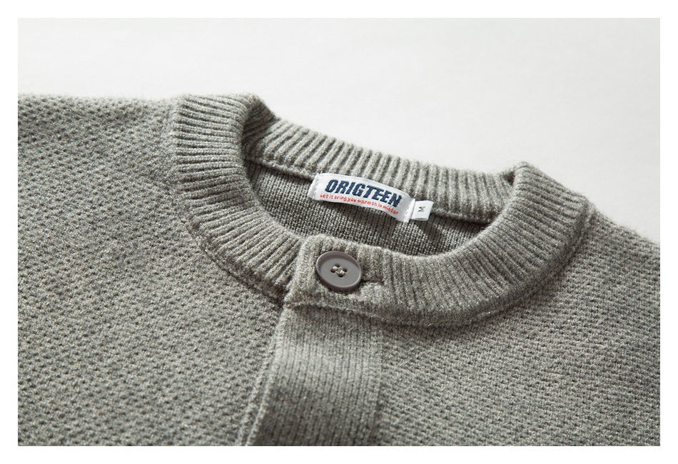 Close-up of a gray knit cardigan's ribbed neckline, top button, front placket, and sewn neck label.