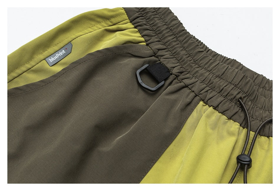Close-up of the shorts' elastic waistband, drawcord loop and color-block panels, with a small sewn-in label.