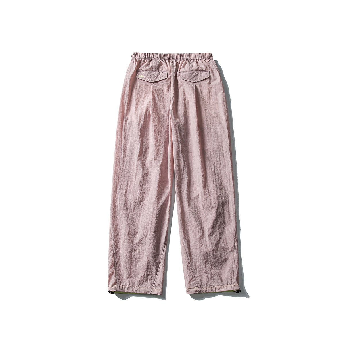 Back view of pale pink loose-fitting pants with an elastic waist and two flap pockets, displayed flat on white.
