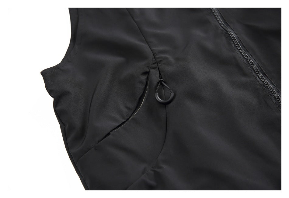 Close-up of a black sleeveless jacket showing a curved seam and a small loop beside the front zipper.