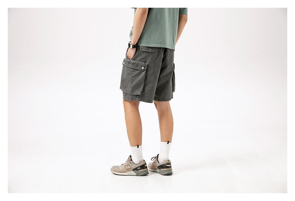 Rear view of a model wearing charcoal gray cargo shorts with large flap pockets.