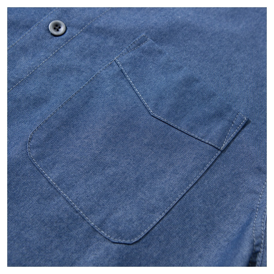 Close-up of a blue shirt's stitched chest pocket and a gray button.
