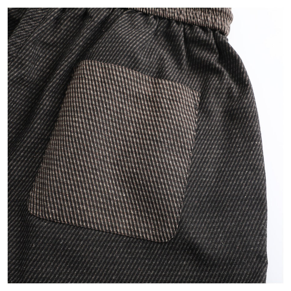 Close-up of a rectangular patch pocket on dark brown and black finely striped fabric.