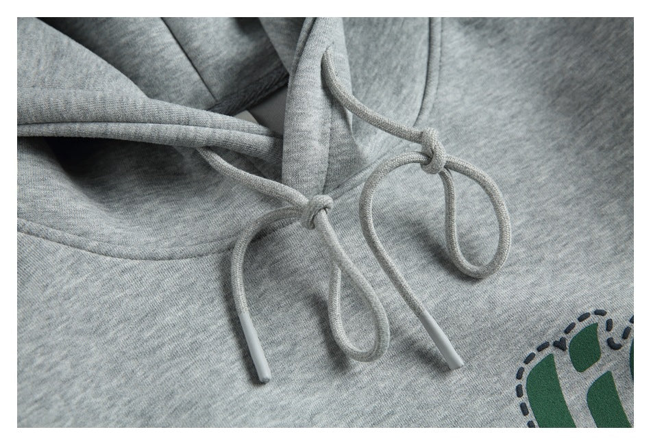 Close-up of the gray hoodie’s knotted drawstrings and aglets, with part of the chest graphic visible.