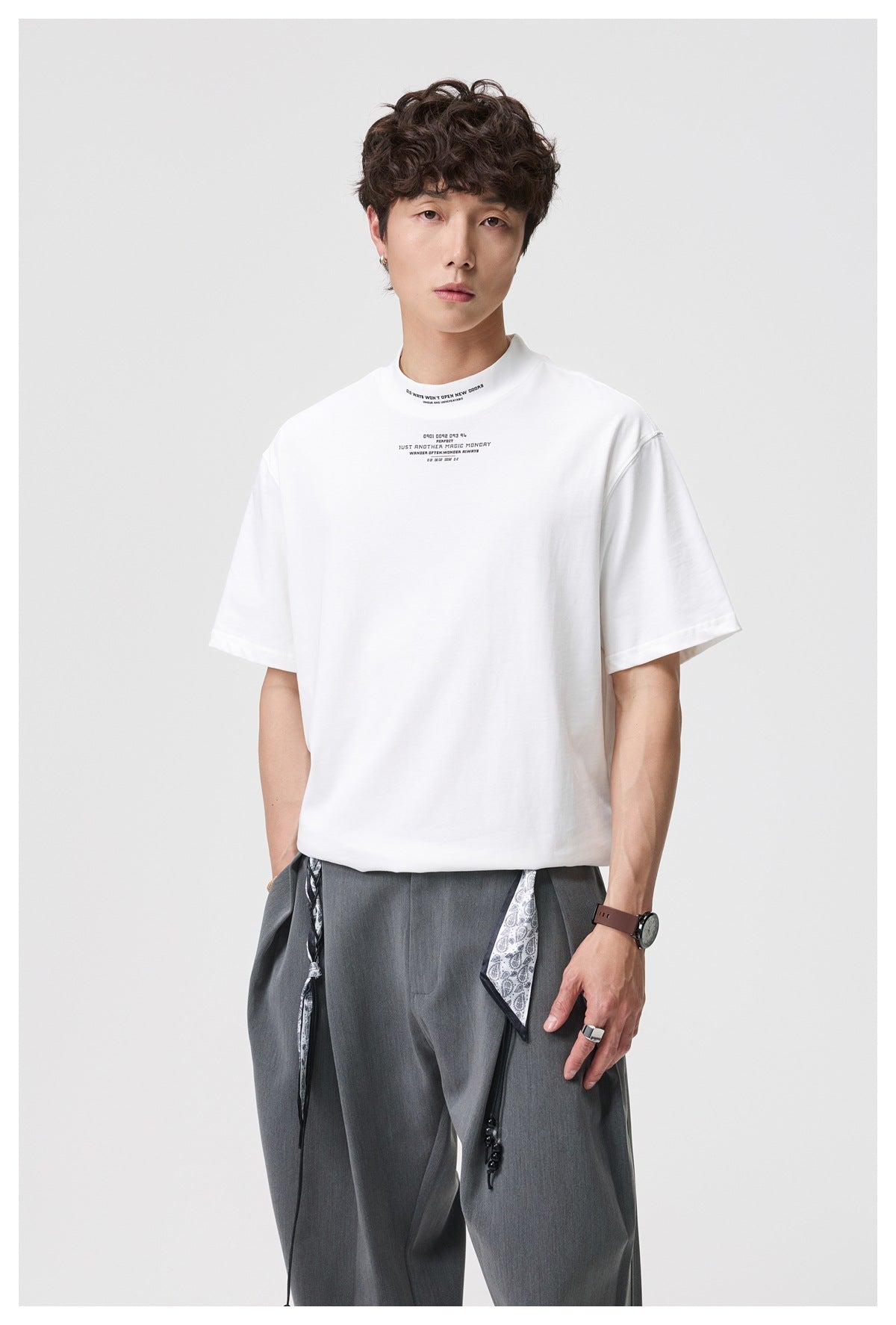 Closer front view of a model wearing a white short-sleeve T-shirt with small chest text.